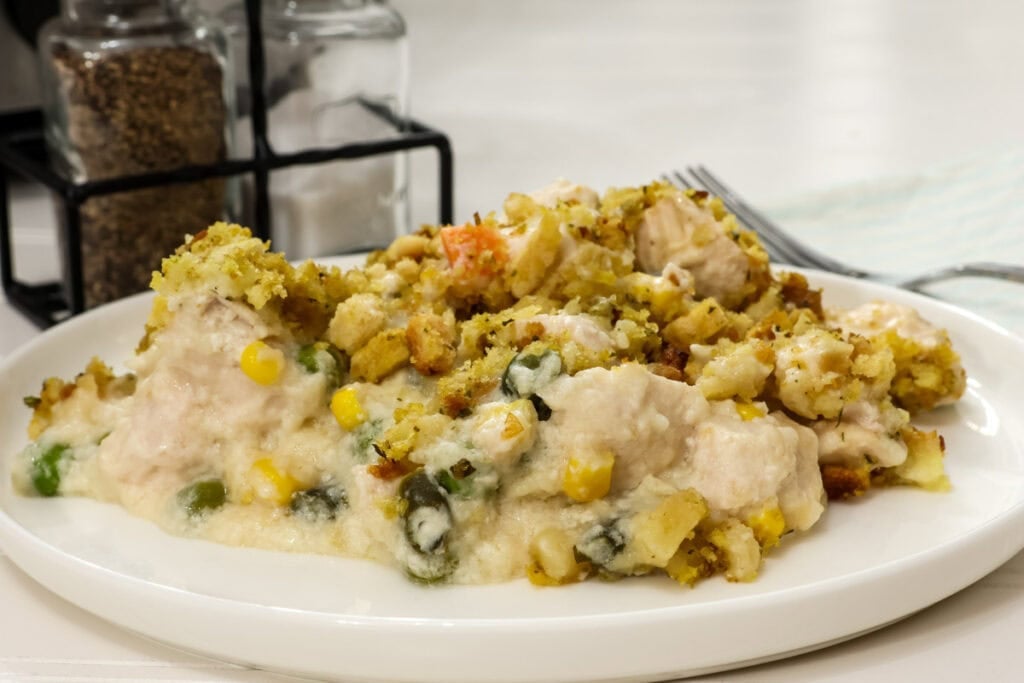 Side view of one serving of slow cooker chicken and stuffing with mixed vegetables on a plate.