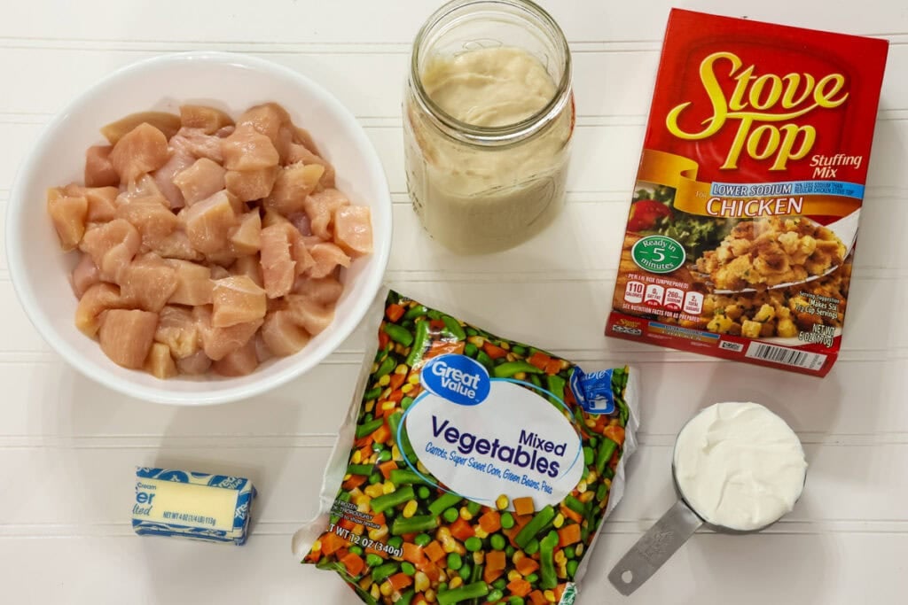 Chicken, stuffing mix, butter, sour cream, cream of chicken soup, and frozen mixed vegetables for slow cooker chicken and stuffing.