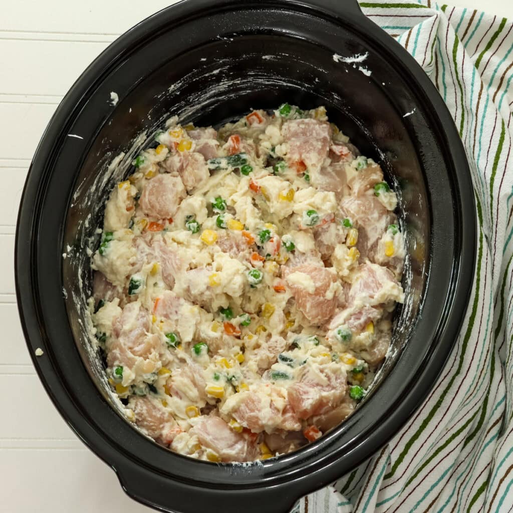 The chicken, vegetables, sour cream and soup mixed together in the crockpot before adding the stuffing on top.